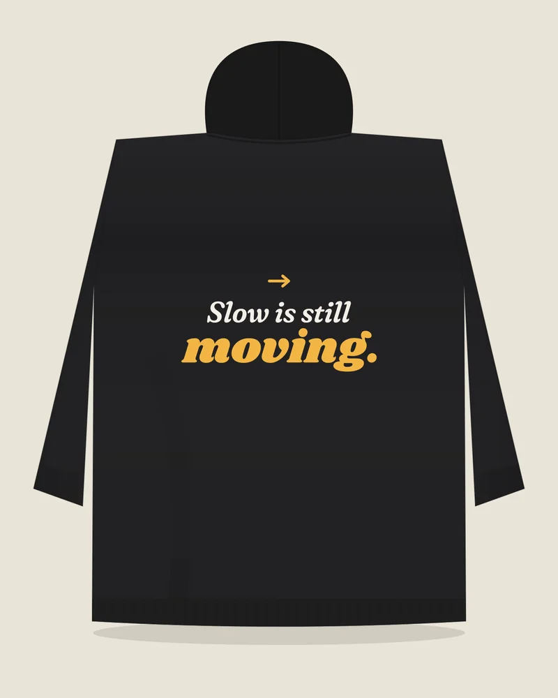 Black hoodie with the print “Slow is still moving.”, back view (illustration)